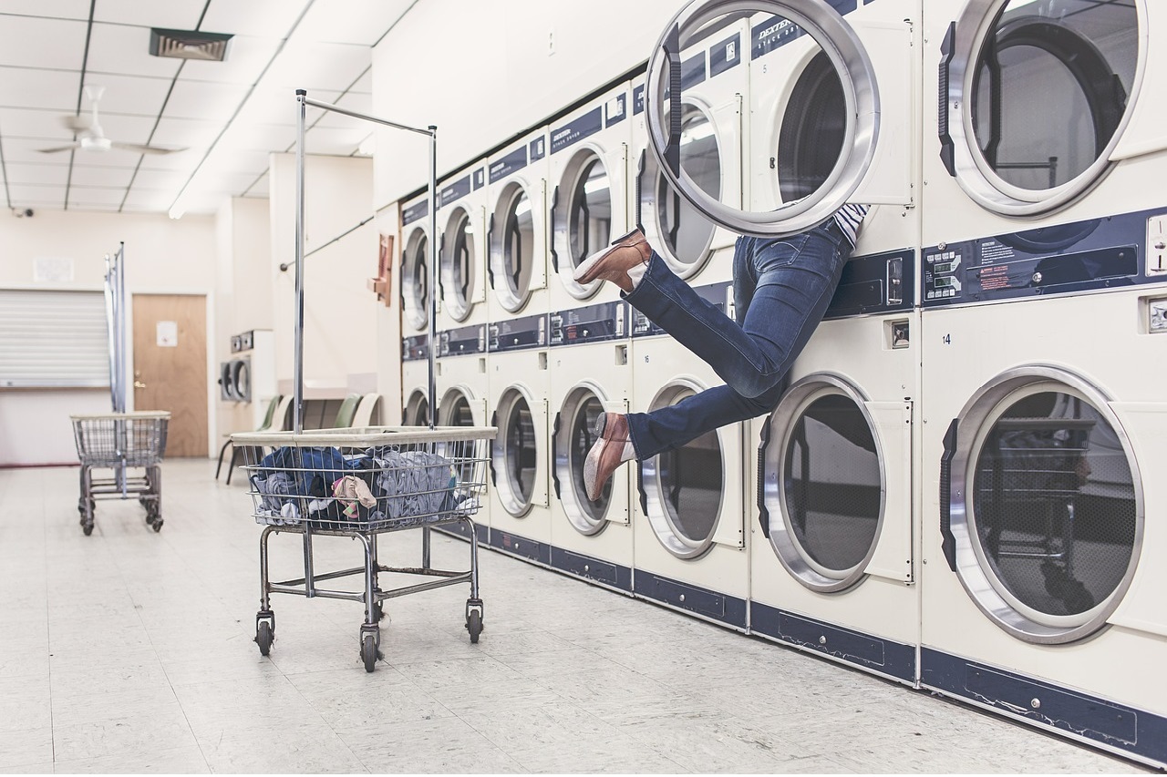 Man Struggling with Washing Machine in a Laundromat